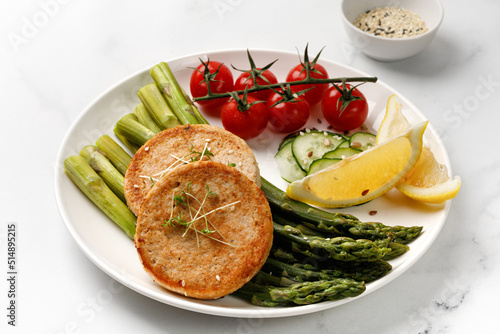 Fried cutlet with vegetables - asparagus, cucumbers and tomatoes cherry. Diet dinner idea, keto diet.