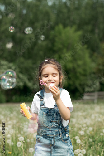 Portrait of a happy little caucasian girl blowing soap bubbles on a summer day in the park.Summer  childhood concept.