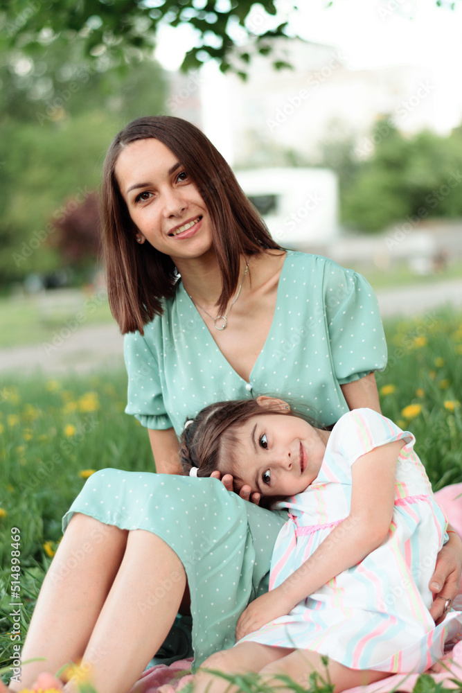 Portrait of a happy mother and daughter resting on the grass on a summer day.Family and summer concept. Portrait of a happy mother and daughter resting on the grass on a summer day.Family and summer concept.