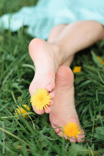 Bare female feet on the grass with yellow dandelions between the toes.Summer,closeness to nature, simple living.