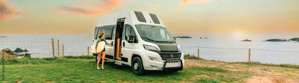 Young woman with wetsuit and surfboard closing the door of her camper van to go surfing Young woman with wetsuit and surfboard closing the door of her camper van to go surfing
