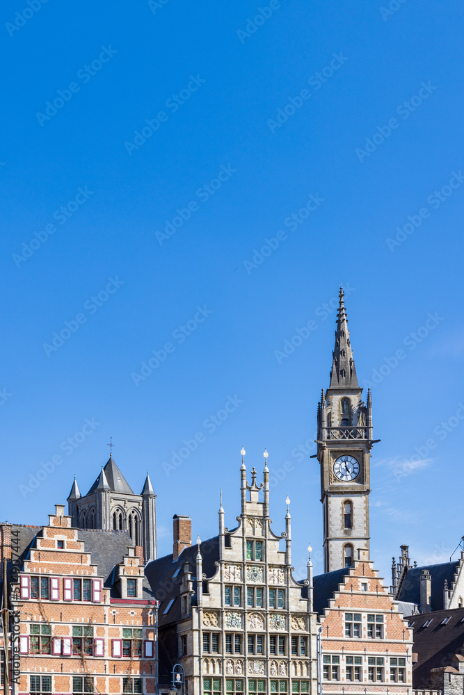 Ancient gable houses and clock tower along the Korenlei in Ghent port city in northwest Belgium during a sunny day