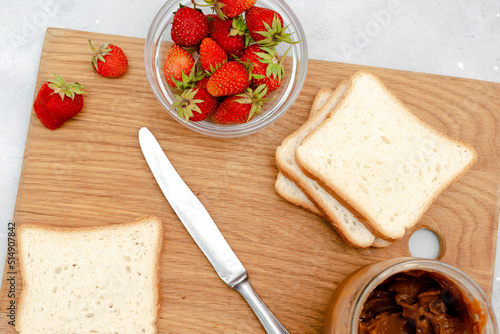 Sandwich toast bread with peanut butter, strawberry,nuts on wooden cutting board. kids childrens baby's sweet dessert, healthy breakfast,lunch, food art on gray background,top view,flatlay