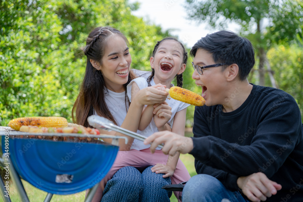 Φωτογραφία Asian family laughs and smiles as they eat barbecue in courtyard to house