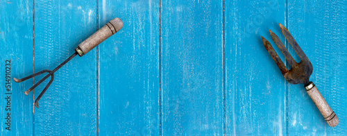 Hand fork and rake on blue plank wooden floor on background.  Hand Tools Home Gardening Tools Accessories.