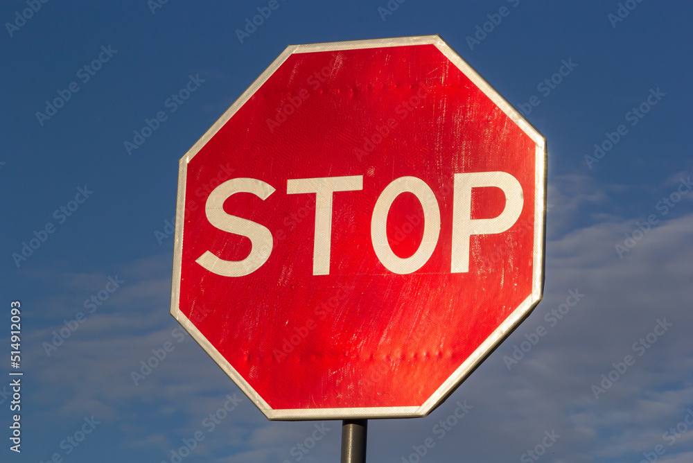 Red Stop Sign with Blue Sky and Clouds Background