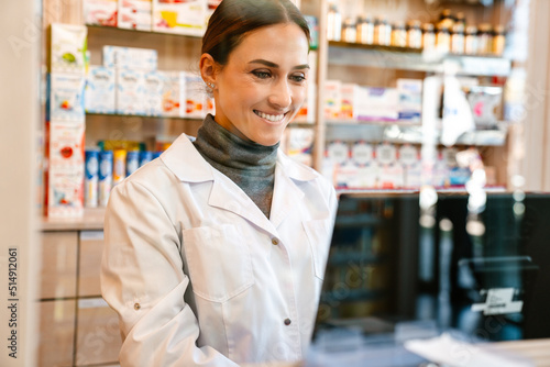 Fotografi White apothecary smiling while working with till at pharmacy