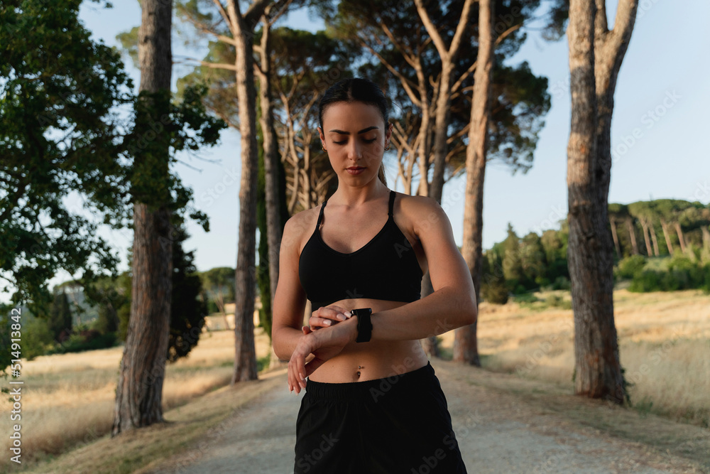 Young woman checking time in smart watch on road Young woman checking time in smart watch on road