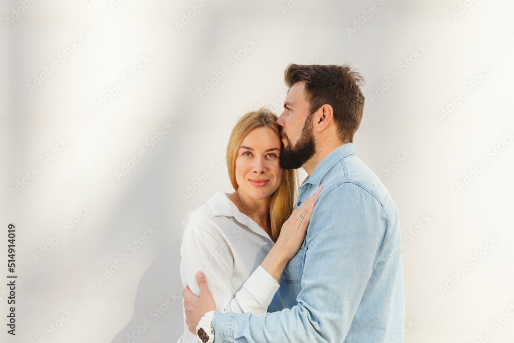 Man embracing blond woman standing in front of wall Man embracing blond woman standing in front of wall