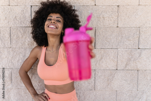 Smiling Afro woman showing pick water bottle