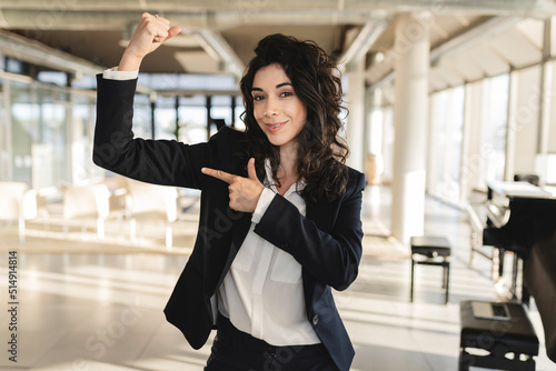 Businesswoman pointing at muscle in office photo