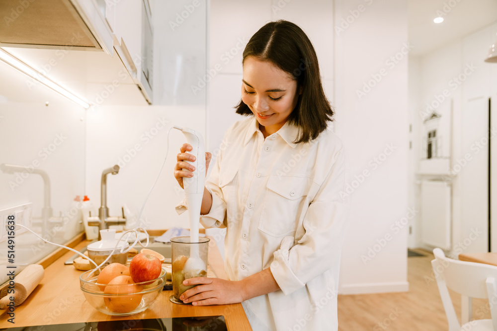 Young cute beautiful smiling asian girl cooking smoothie Young cute beautiful smiling asian girl cooking smoothie