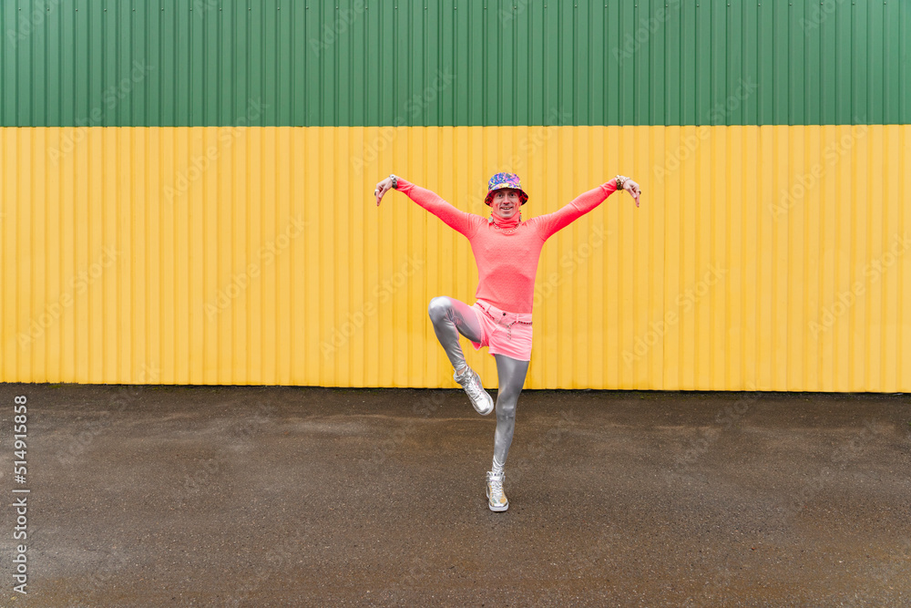 Mature man standing on one leg in front of yellow and green wall Mature man standing on one leg in front of yellow and green wall