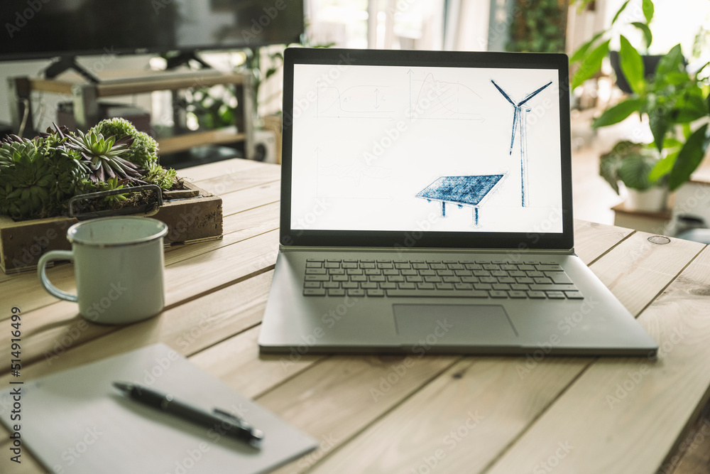 Solar panel and wind turbine on screen of laptop at home Solar panel and wind turbine on screen of laptop at home