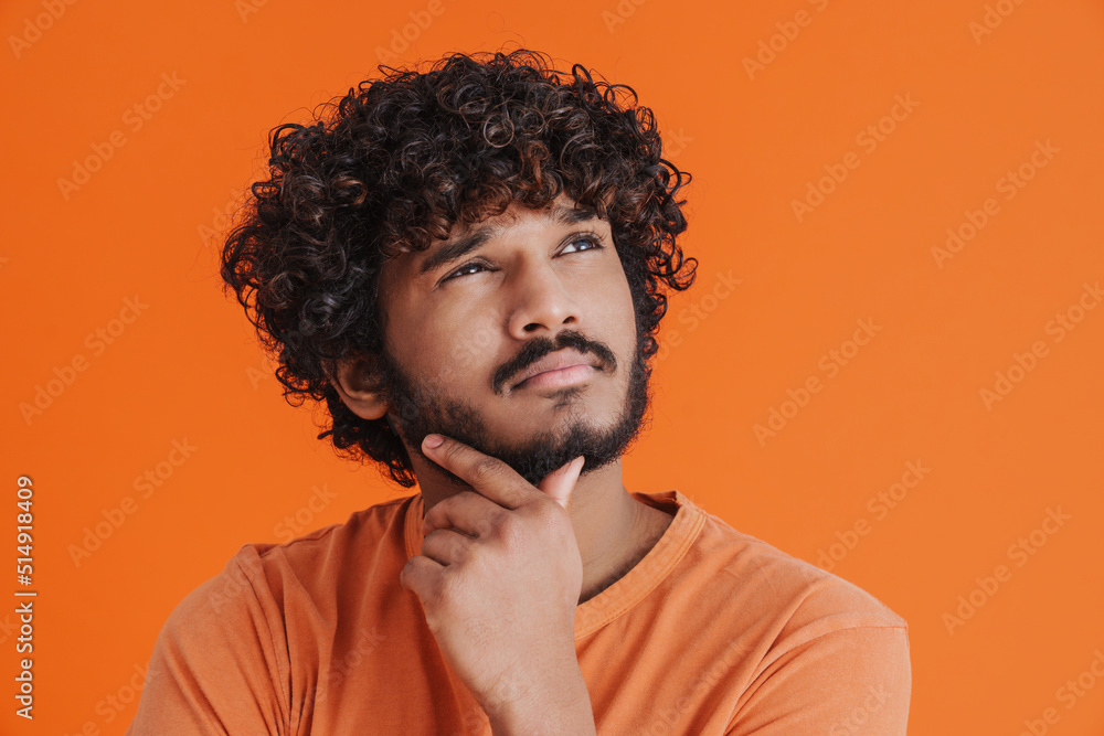 Young indian handsome thoughtful man looking aside touching his chin Young indian handsome thoughtful man looking aside touching his chin
