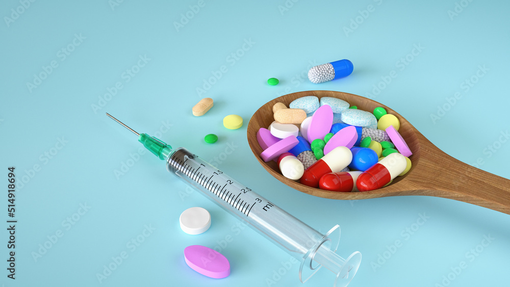 Colorful pills and capsule tablets in wooden spoon with syringe on blue background. Medical or healthy concept.