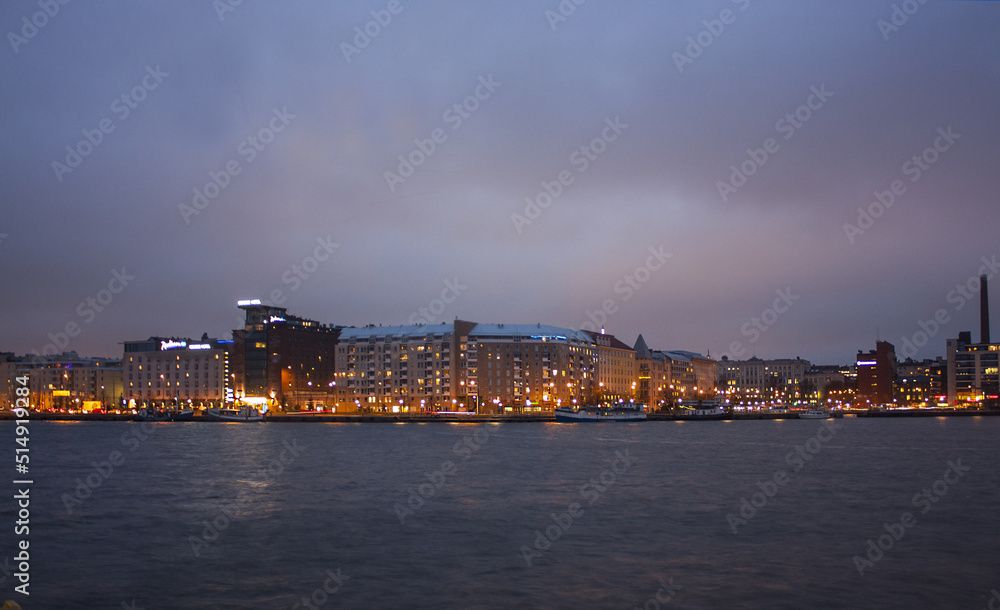 Traditional buildings along the waterfront reflecting at night in the water in Helsinki, Finland