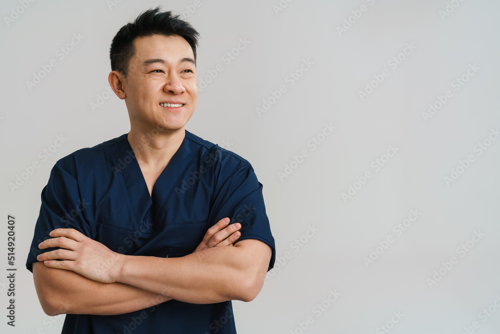 Adult asian man wearing medical uniform posing at camera Adult asian man wearing medical uniform posing at camera