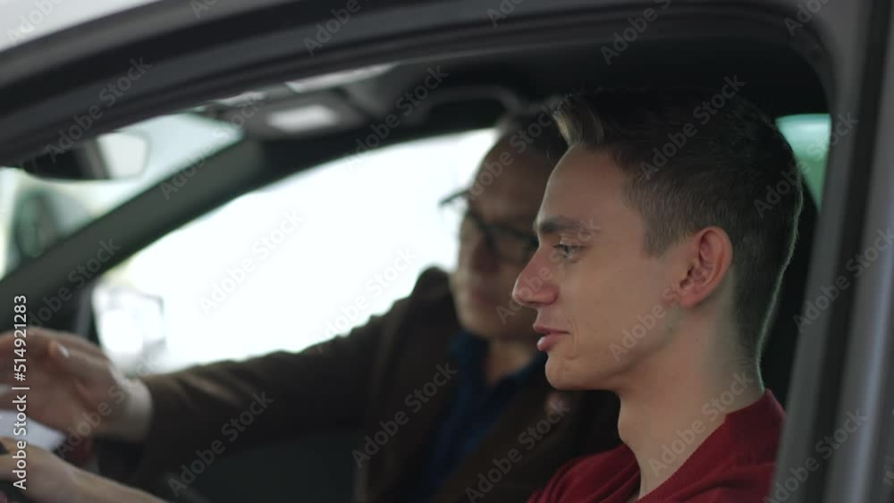 Male customers are sitting inside new car and talking while shopping in dealership office spbd. 4k Close view of young son, elderly father sit in car and talk with smiles, ready to make test drive and Male customers are sitting inside new car and talking while shopping in dealership office spbd. 4k Close view of young son, elderly father sit in car and talk with smiles, ready to make test drive and