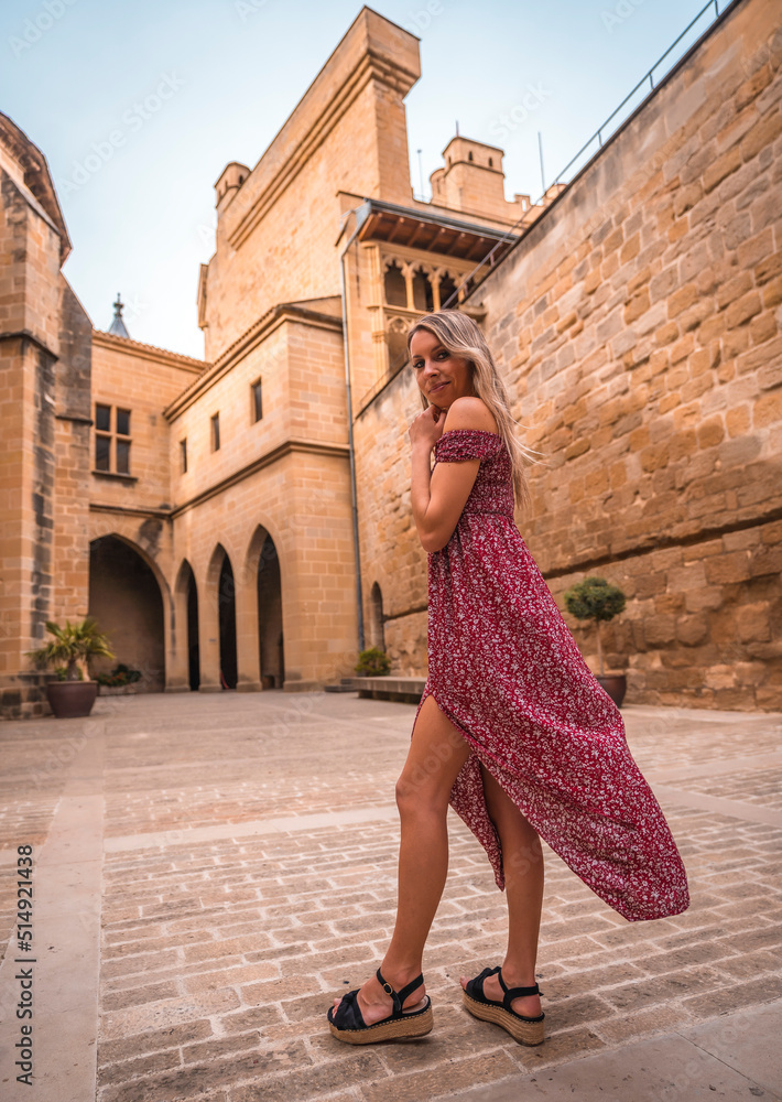 Portrait of a blonde woman in a medieval castle wearing a red dress, enjoying