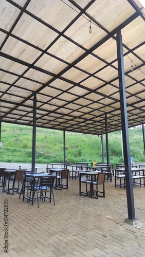 An outdoor restaurant with rows of empty benches and tables in a tourist area in the Cicalengka area, Indonesia
