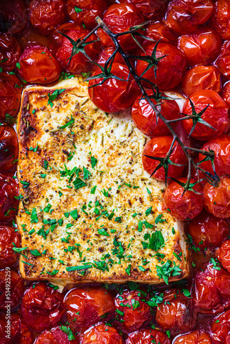 Baked feta cheese with tomatoes in dish. Trendy homemade recipe.