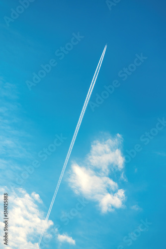 Airplane vapor trail or contrail pattern on blue sky with clouds