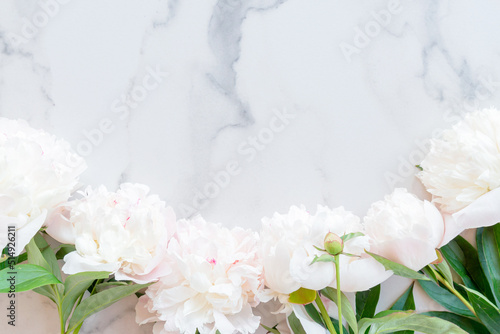 Flat lay composition with pink peony flowers on a marble background with copy space for text or design