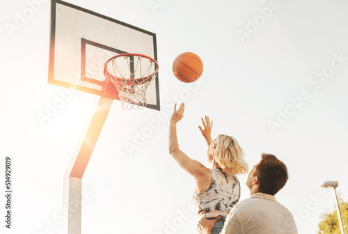 summer holidays, sport and people concept - happy young couple with ball playing on basketball playground