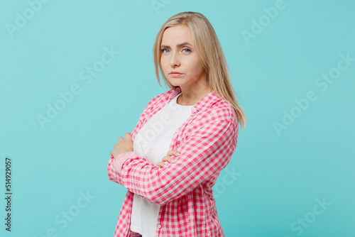 Young sad unhappy caucasian woman she 30s wears pink shirt white t-shirt hold hands crossed folded look camera isolated on plain pastel light blue background studio portrait. People lifestyle concept.
