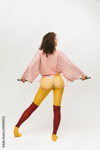 Back view of young fashionable girl in avant-garde style outfit over white background. Vivid style, beauty, queer, freak, fashion concept. photo