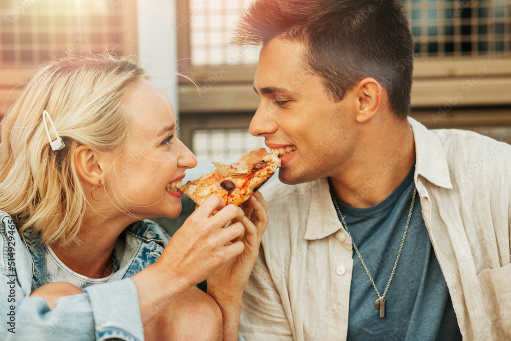food and people concept - happy young couple eating takeaway pizza outdoors food and people concept - happy young couple eating takeaway pizza outdoors