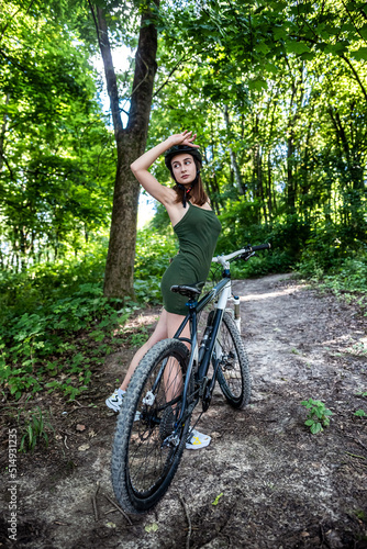Happy young girl rides a bicycle in the forest on hot summer day © RomanR