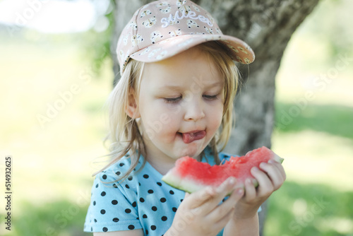 cute little girl eating watermelon outdoors in summertime. Child and watermelon in summer. 
