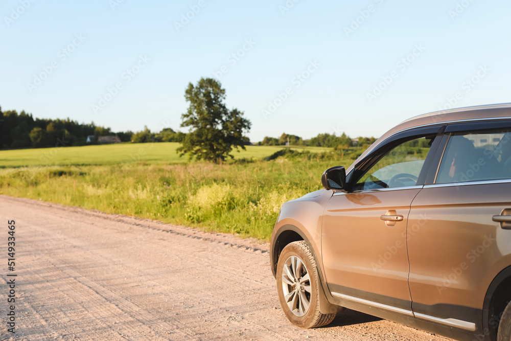 Car parked in countryside on rural landscape and blue sky at sunset. Summer, transportation, traveling concept