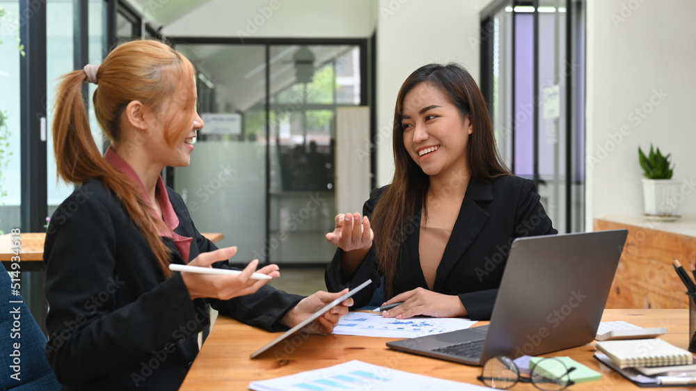 Two happy business colleagues discussing business project, working together in office Two happy business colleagues discussing business project, working together in office
