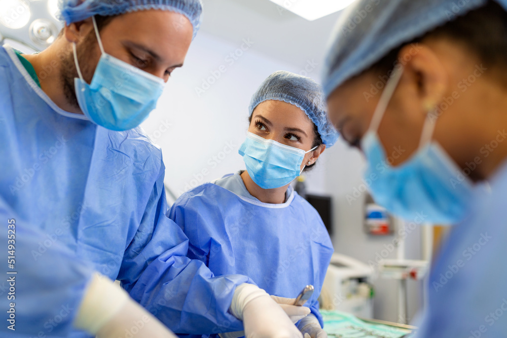Surgeons in a light operating room perform plastic surgery, a team of male and female doctors perform reconstructive surgery. Surgeons in a light operating room perform plastic surgery, a team of male and female doctors perform reconstructive surgery.