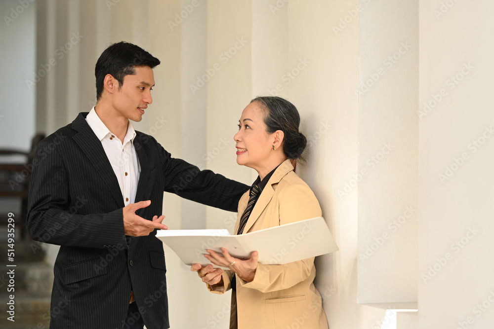 Two business people having a discussion and standing under the office building Two business people having a discussion and standing under the office building