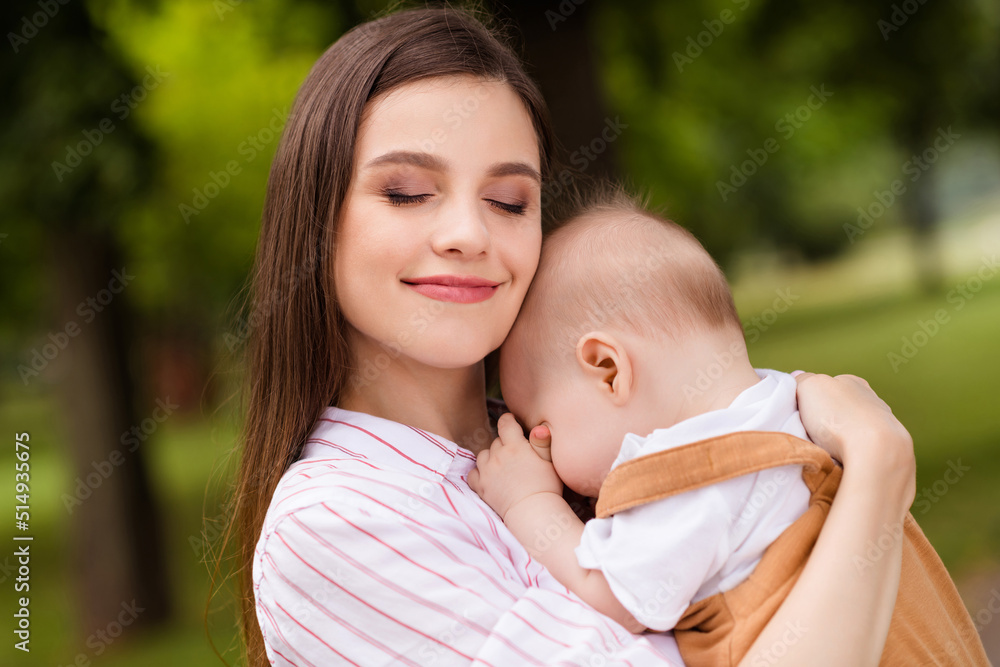 Family portrait of loving attractive mom cuddle dream sleeping son infant outdoors wearing casual clothes Family portrait of loving attractive mom cuddle dream sleeping son infant outdoors wearing casual clothes