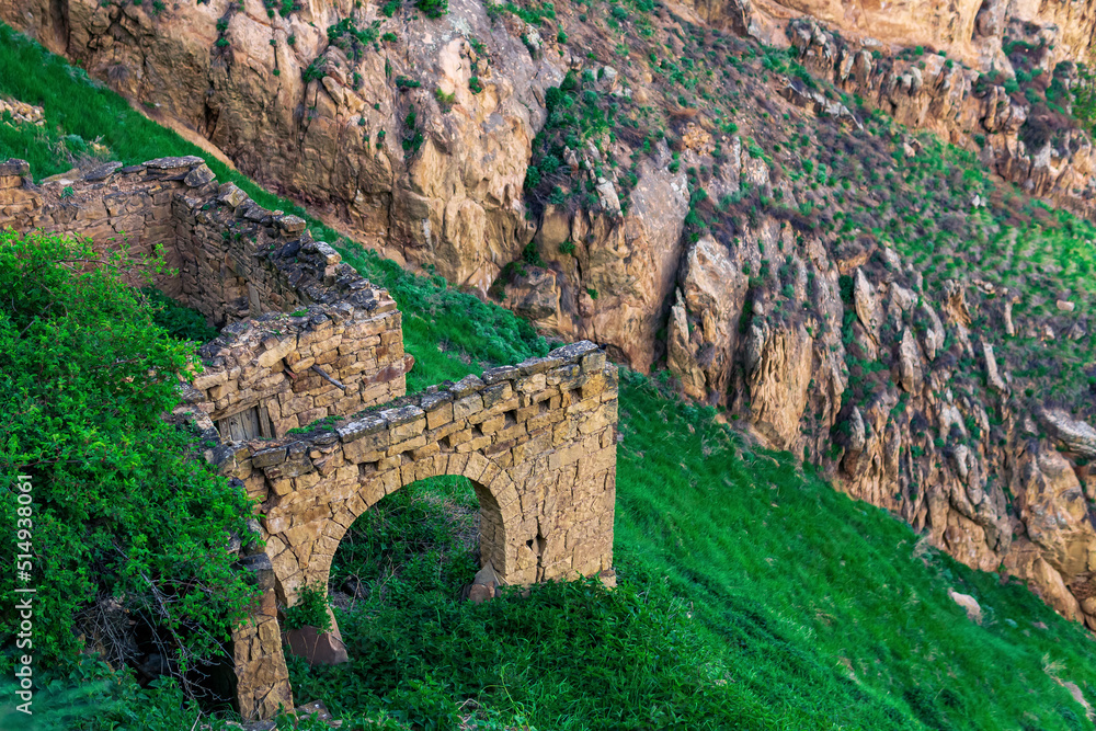 ruins of stone walls on a steep mountain slope in an abandoned highlanders village Gamsutl in Dagestan