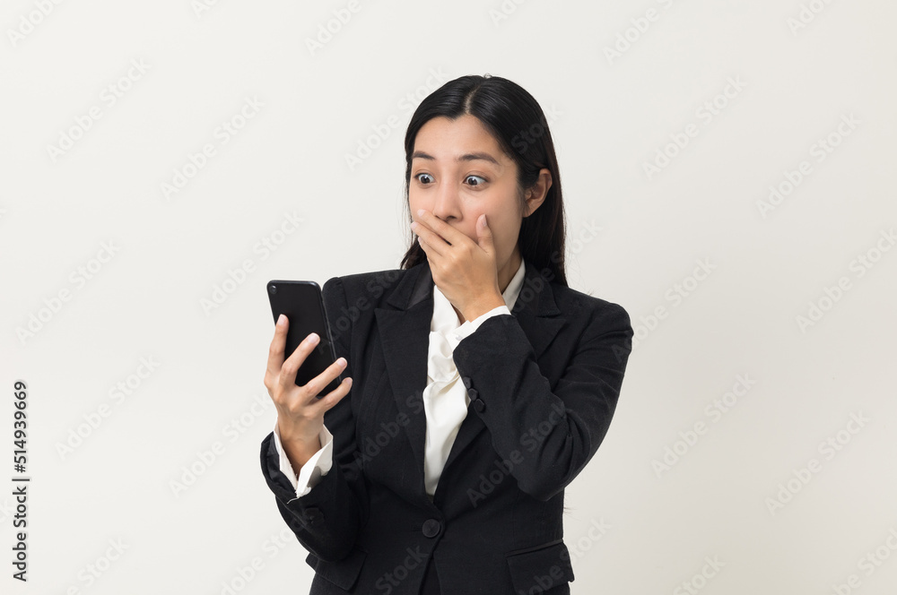 Happy young asian business woman using smartphone on isolated white background. Attractive female in suit holding cell phone feeling happy. Portrait shot in studio. Happy young asian business woman using smartphone on isolated white background. Attractive female in suit holding cell phone feeling happy. Portrait shot in studio.