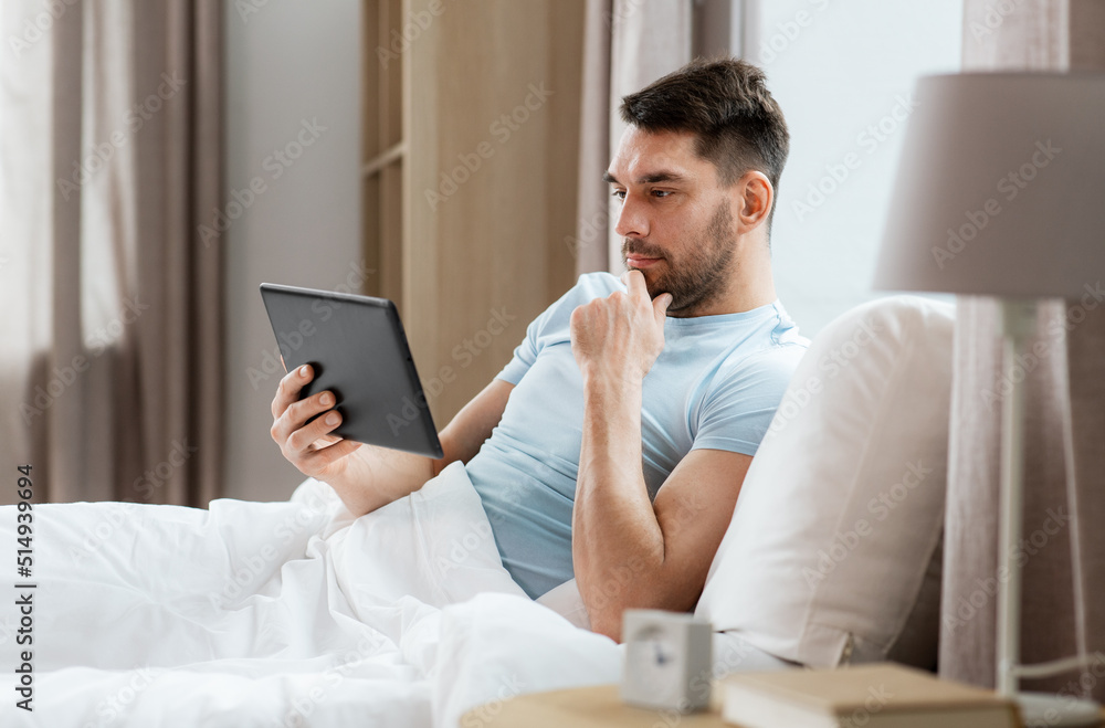 technology, internet and people concept - man with tablet pc computer in bed at home bedroom
