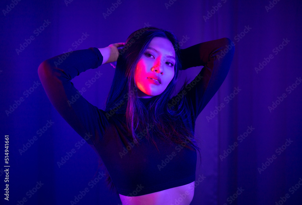 Stylish sexy woman in trendy. Beautiful young asian woman standing pose with neon light. Asia Pretty asian female in the dark room. Fashion shot.