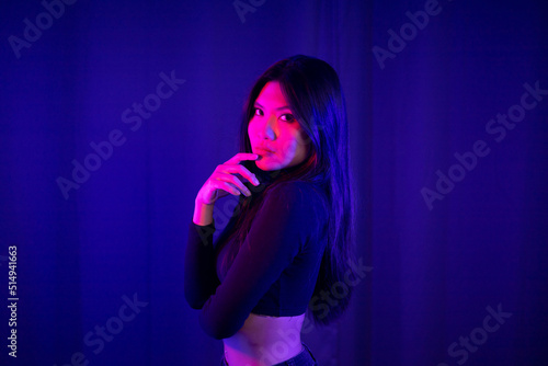 Stylish sexy woman in trendy. Beautiful young asian woman standing pose with neon light. Asia Pretty asian female in the dark room. Fashion shot. © Chanakon
