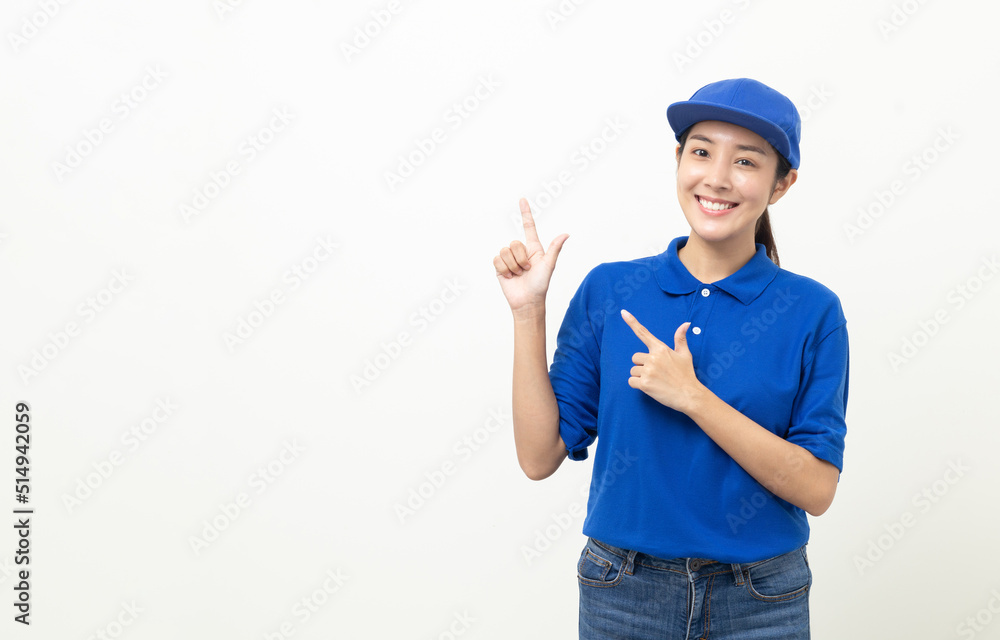 Happy delivery asian woman in blue uniform standing pointing the finger to blank space for text advertise on isolated white background. Smiling female delivery service worker.