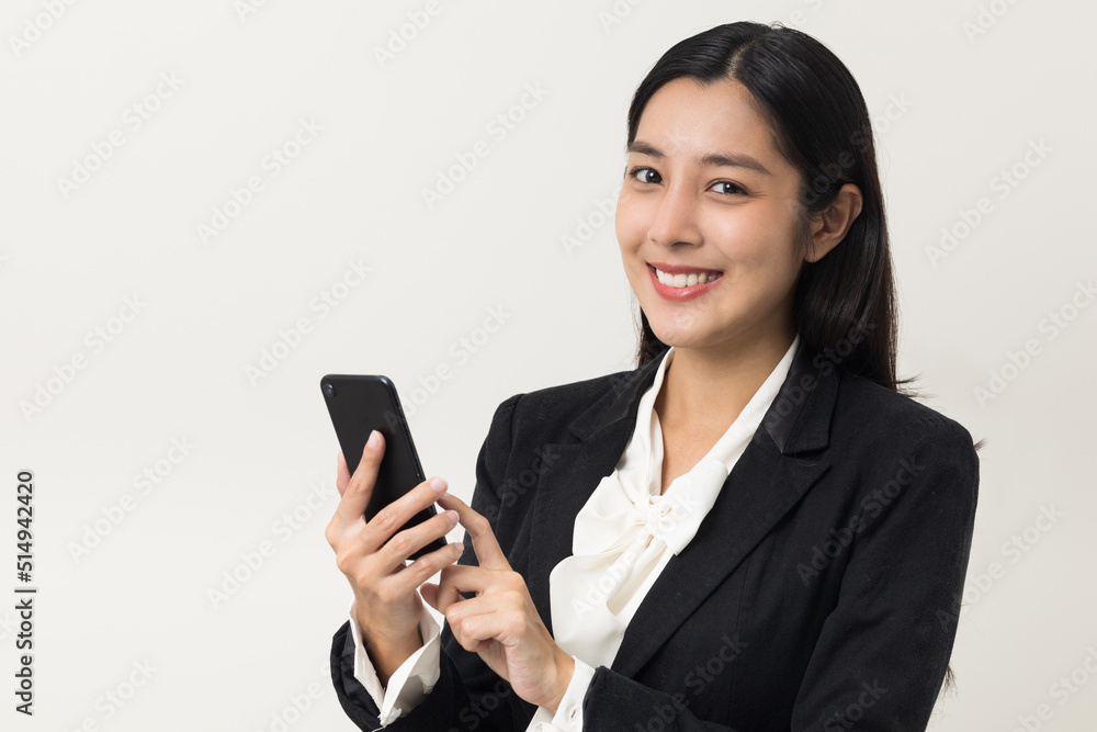 Happy young asian business woman using smartphone on isolated white background. Attractive female in suit holding cell phone feeling happy. Portrait shot in studio. Happy young asian business woman using smartphone on isolated white background. Attractive female in suit holding cell phone feeling happy. Portrait shot in studio.