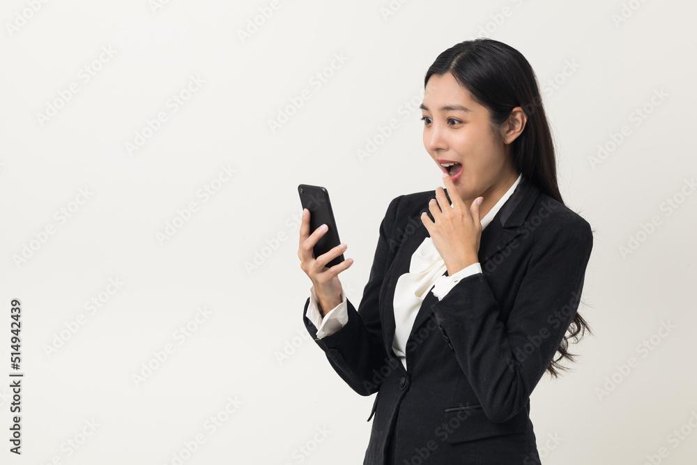 Happy young asian business woman using smartphone on isolated white background. Attractive female in suit holding cell phone feeling happy. Portrait shot in studio. Happy young asian business woman using smartphone on isolated white background. Attractive female in suit holding cell phone feeling happy. Portrait shot in studio.
