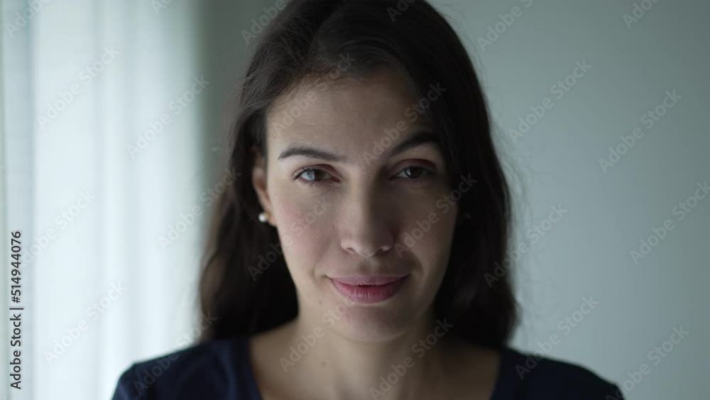Portrait of woman in 30s with serious expression. Closeup face of person looking at camera standing by window Portrait of woman in 30s with serious expression. Closeup face of person looking at camera standing by window