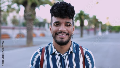 Face portrait of young hispanic latino man in city street - Happy millennial guy smiling at camera while standing outdoor photo