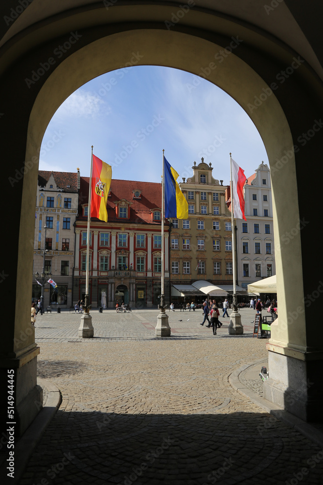 Naklejka premium The state flags of Poland and Ukraine flutter on flagpoles on the main square of the city. Friendship between Poland and Ukraine, Help and Solidarity